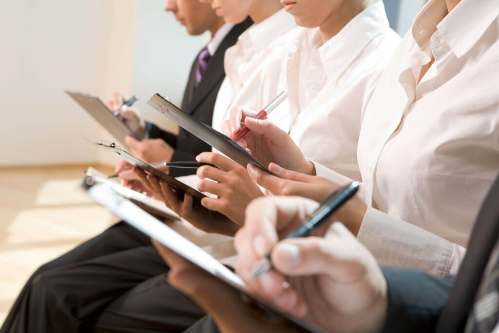 Image of row of business people writing on papers at seminar