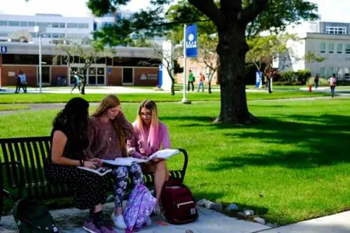 three girls sitting on a bench on campus