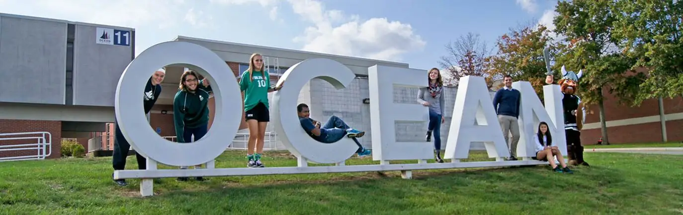 Students standing on the OCEAN sign