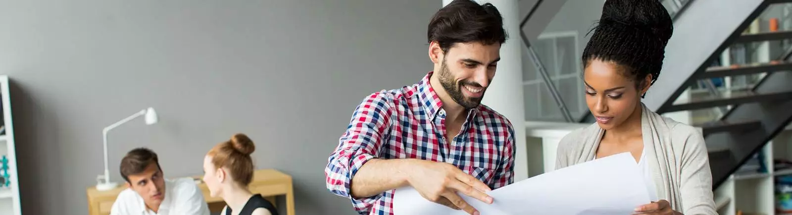 Man and women smiling while reading a paper