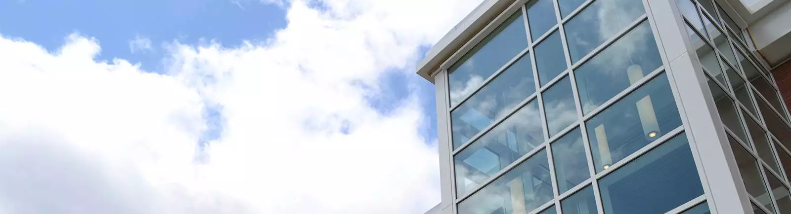 Corner of a building with large windows and sky in the background