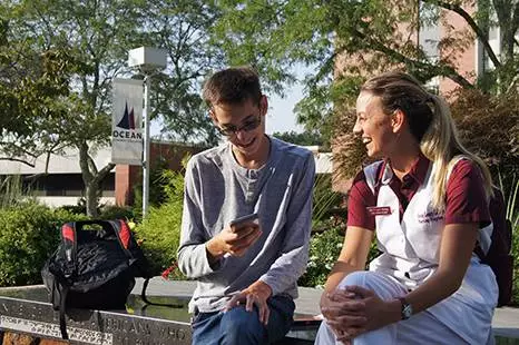 A male and female student laughing on campus