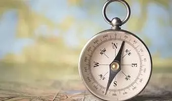 compass standing upright on a wood table