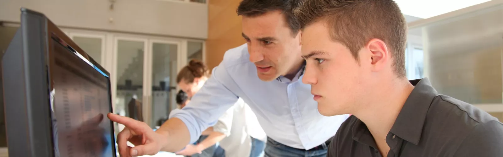 teacher pointing at computer screen with student