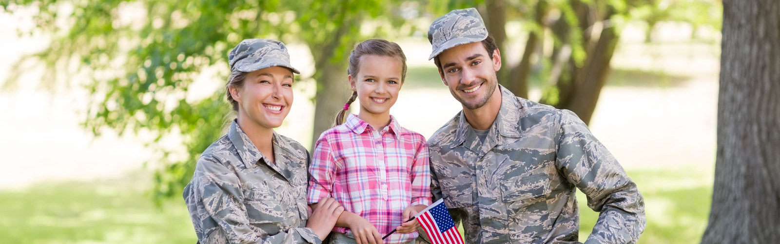 A man and woman each dressed in military fatigues with a little girl between them