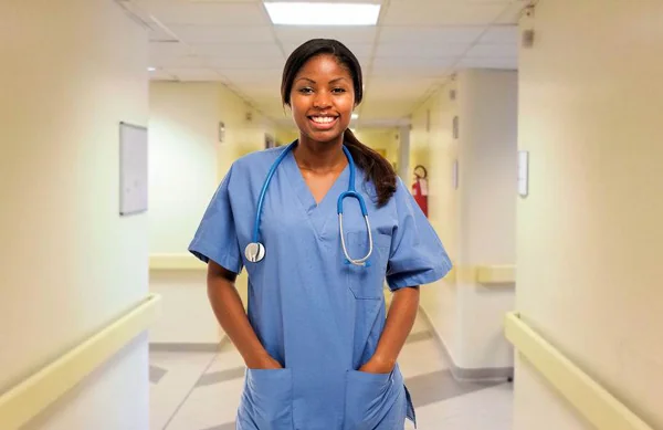 a nurse in blue scrubs with a stethoscope in a hospital hallway