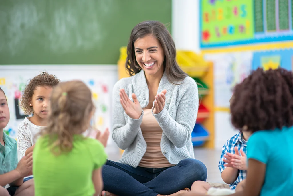 Teacher sitting on floor with K12 students