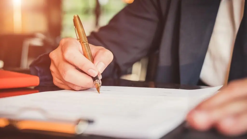 Close up of a hand writing on a piece of paper on a clipboard.