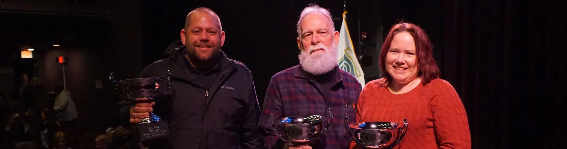 Three people holding trophies