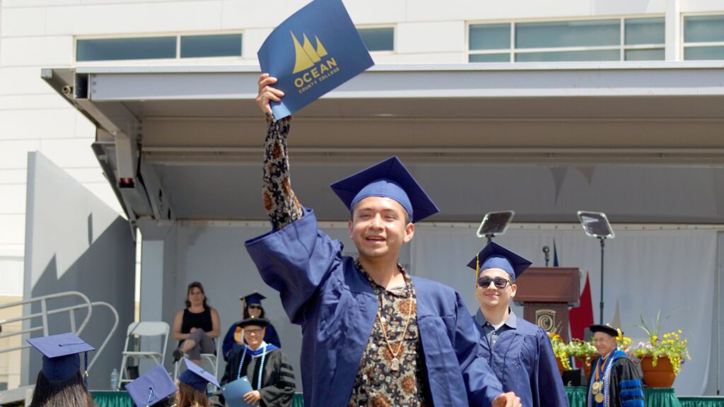 student holding up diploma at graduation 