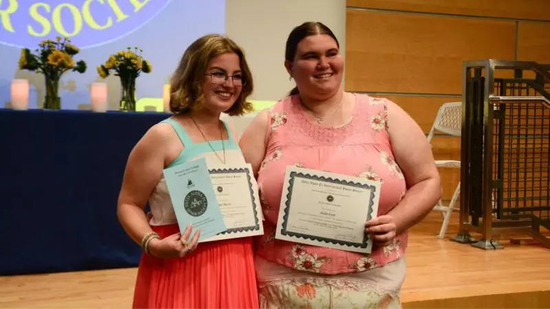 Two female students at the Delta Alpha Pi induction ceremony. 