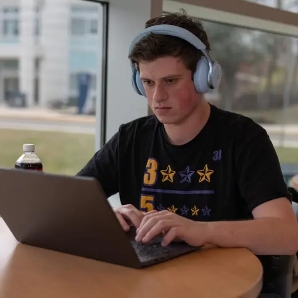 Student working on a laptop wearing headphones.