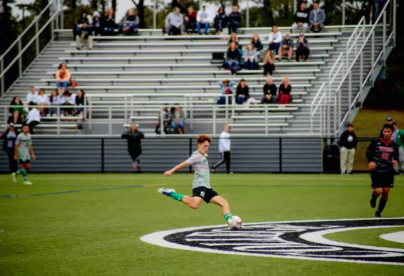 A male student about to kick a soccer ball during a soccer match