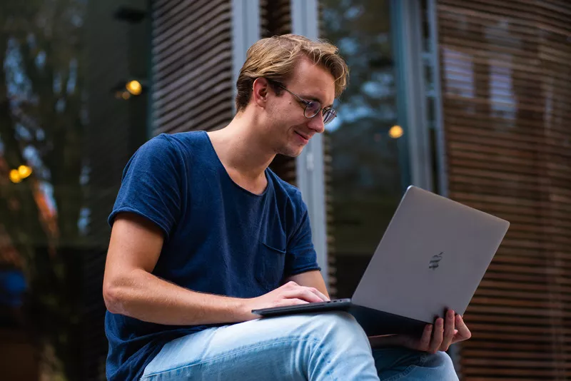 young man using a laptop while sitting outside