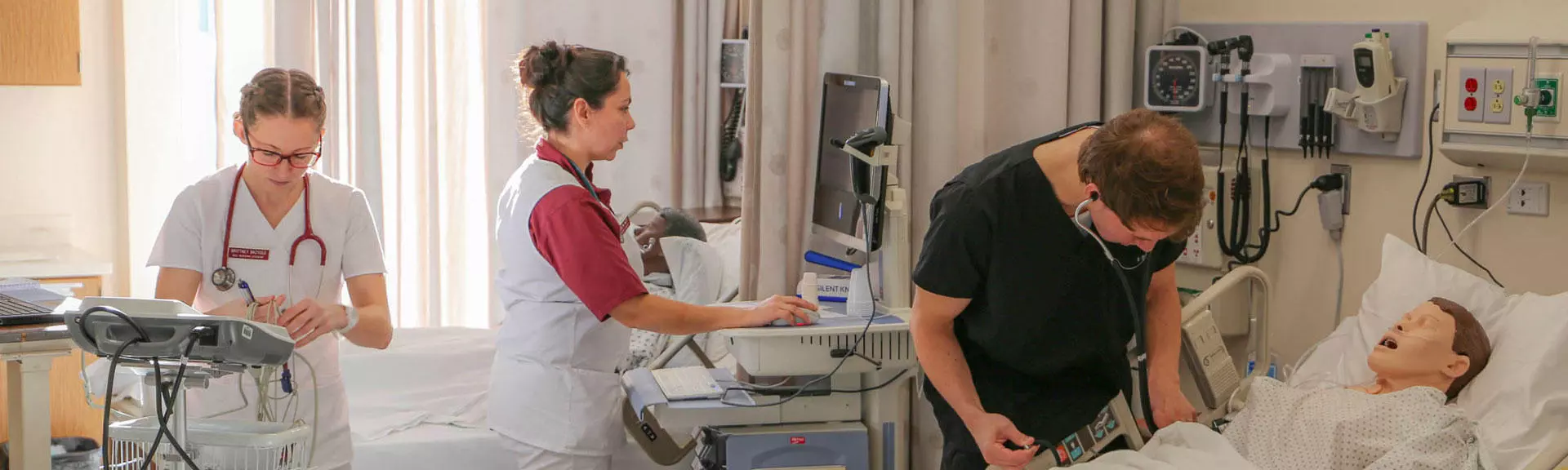 Three healthcare students learning in the simulation lab