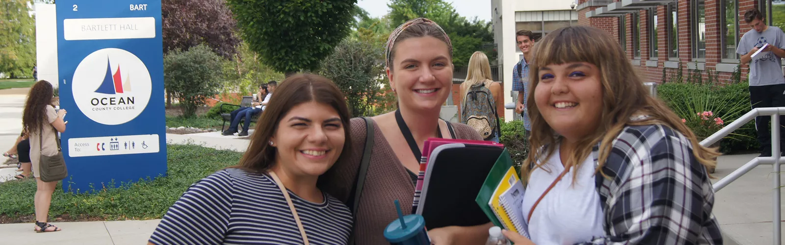 Group of three female students smiling on campus