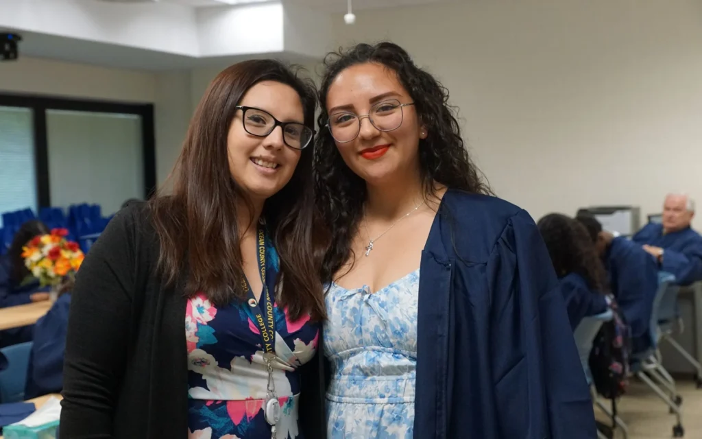 Two females posing in a classroom smiling at the camera