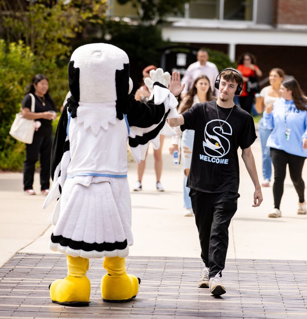 Student high-fiving mascot on the first day of classes