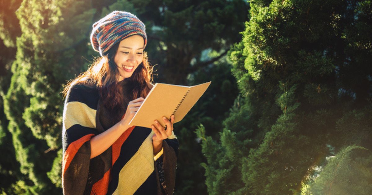 Young woman writing in journal outdoors